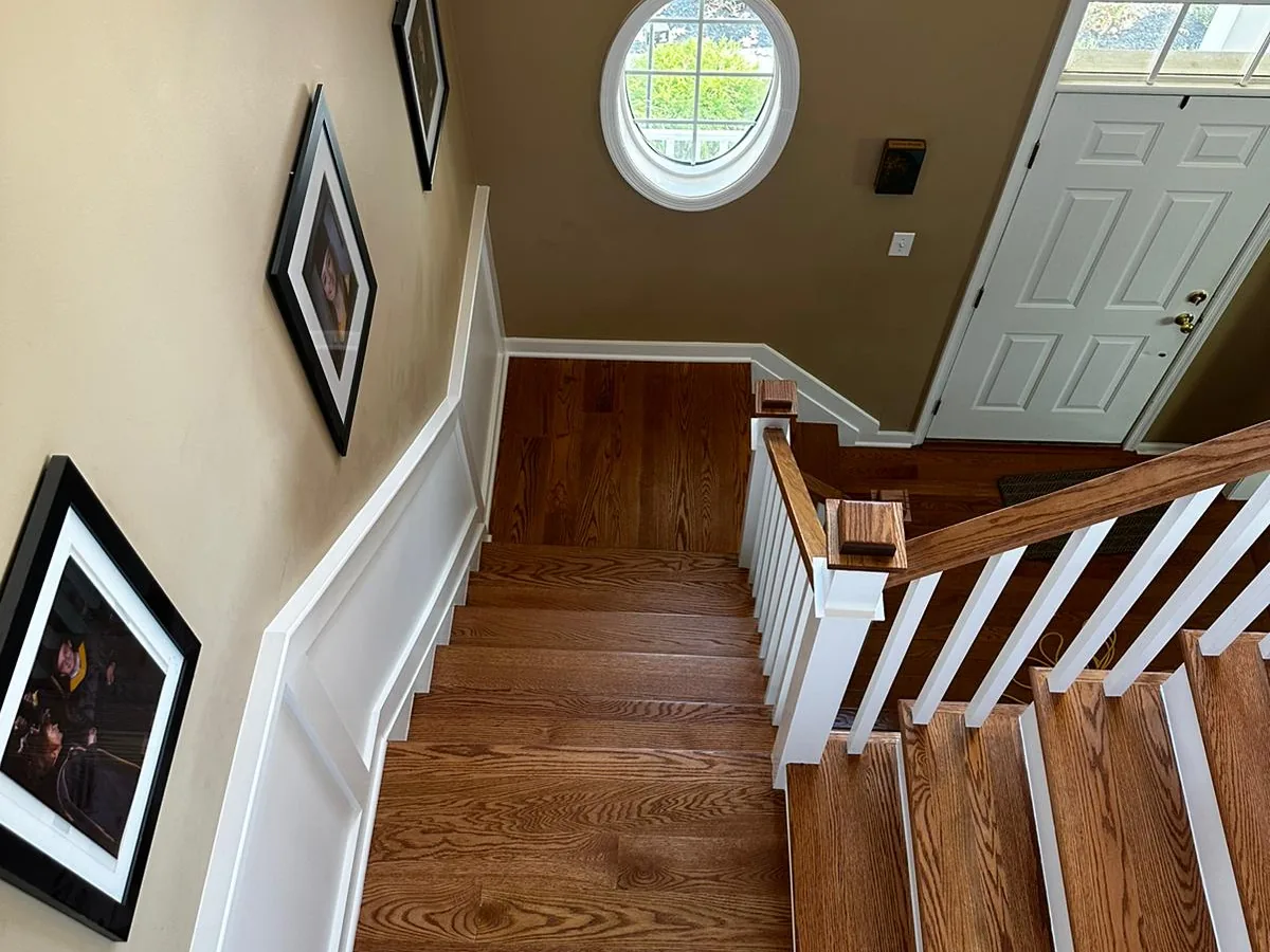 Oak staircase and railing looking down toward a New Jersey front entry